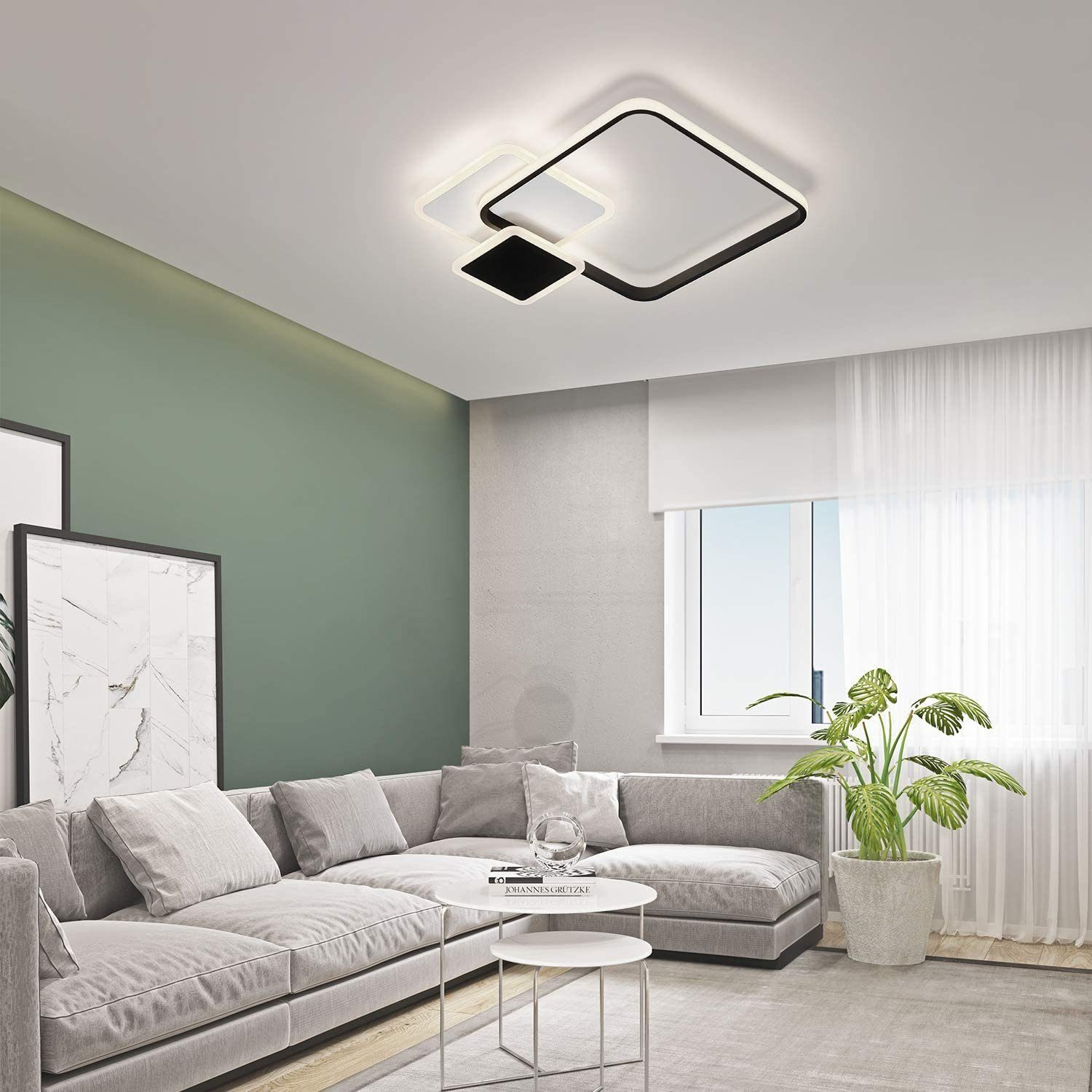 Eine moderne Deckenleuchte in einem Wohnzimmer. Ein Sofa, eine grüne Wand und ein Fenster mit Jalousien sind im Hintergrund.