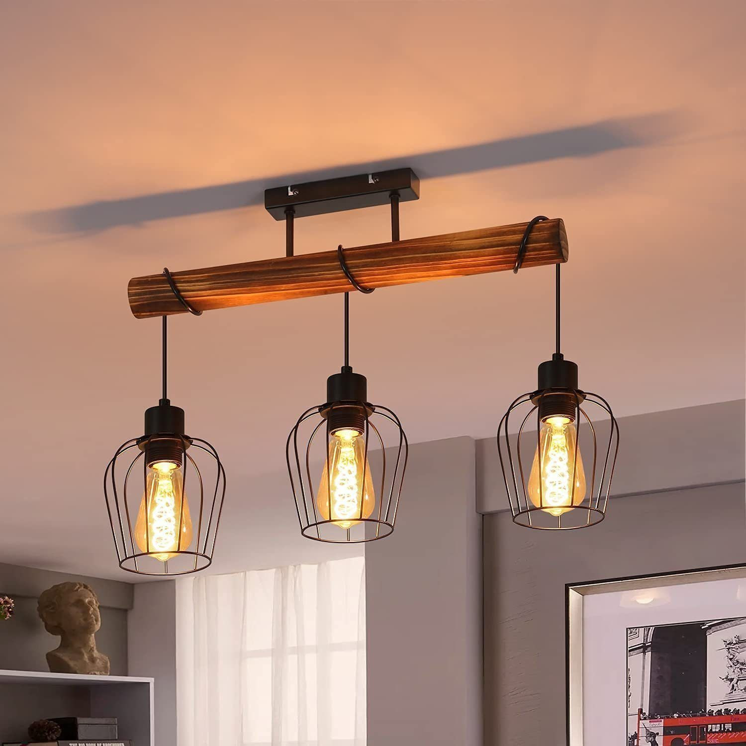 Una trave in legno con tre lampade a sospensione, ognuna con una gabbia attorno alla lampadina.
