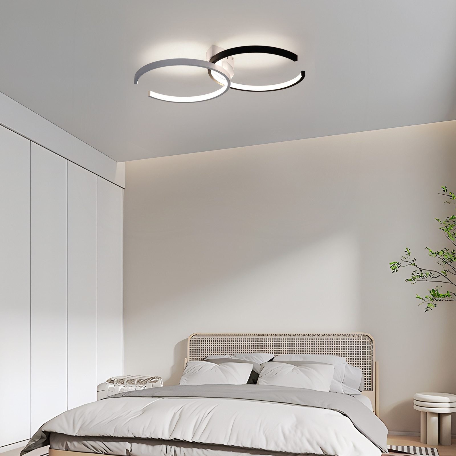 Scena della camera da letto con una moderna luce a soffitto, un letto e un armadio. La luce ha tre forme circolari.