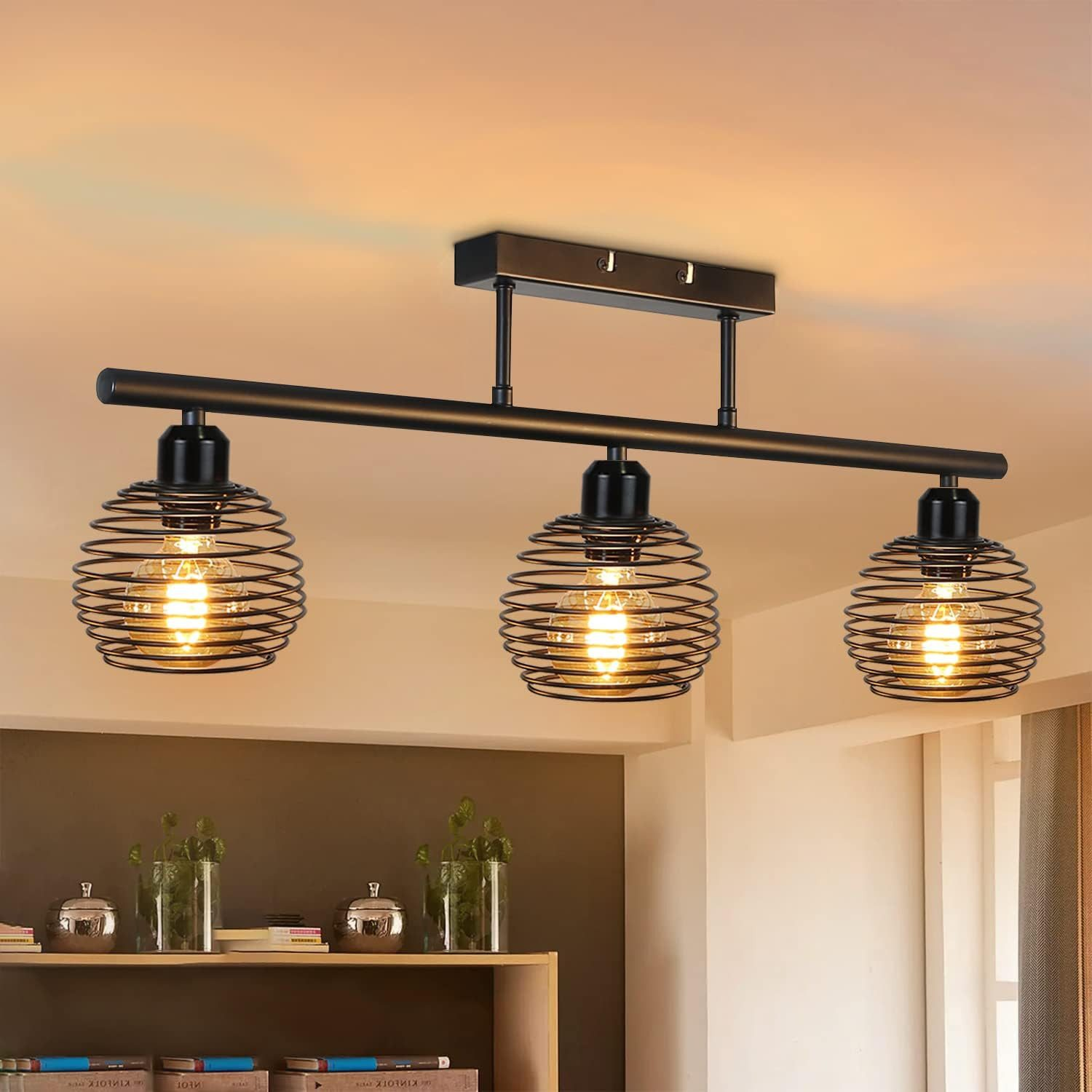 Lampada da soffitto con tre lampade a gabbia di filo e uno sfondo interno scuro.