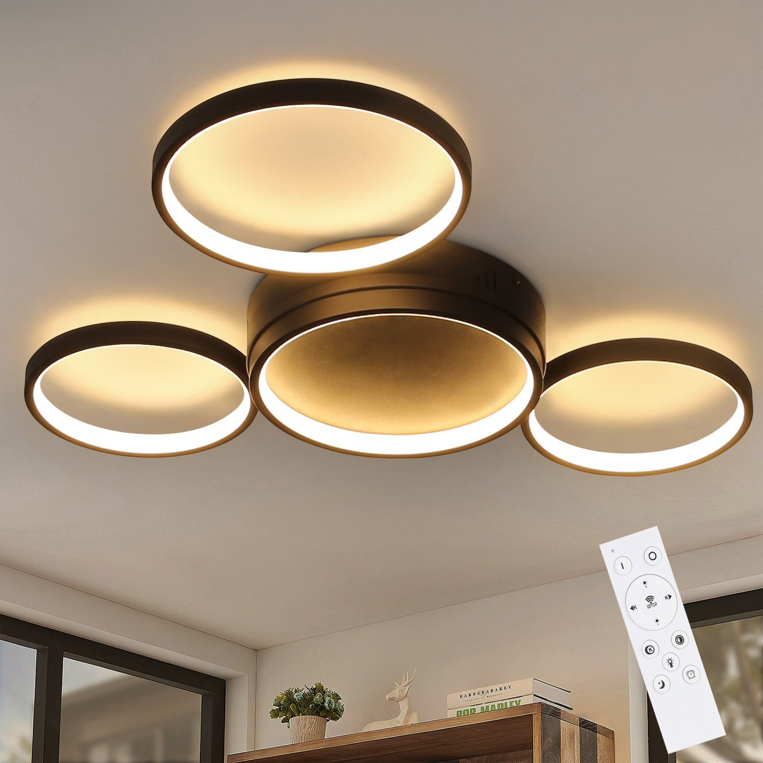 Una lampada da soffitto con quattro luci ad anello e un telecomando. Le luci sono accese.