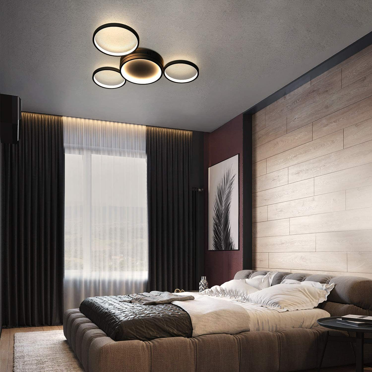 Camera da letto con letto grande, lampada da soffitto moderna, tende scure e quadro sulla parete.