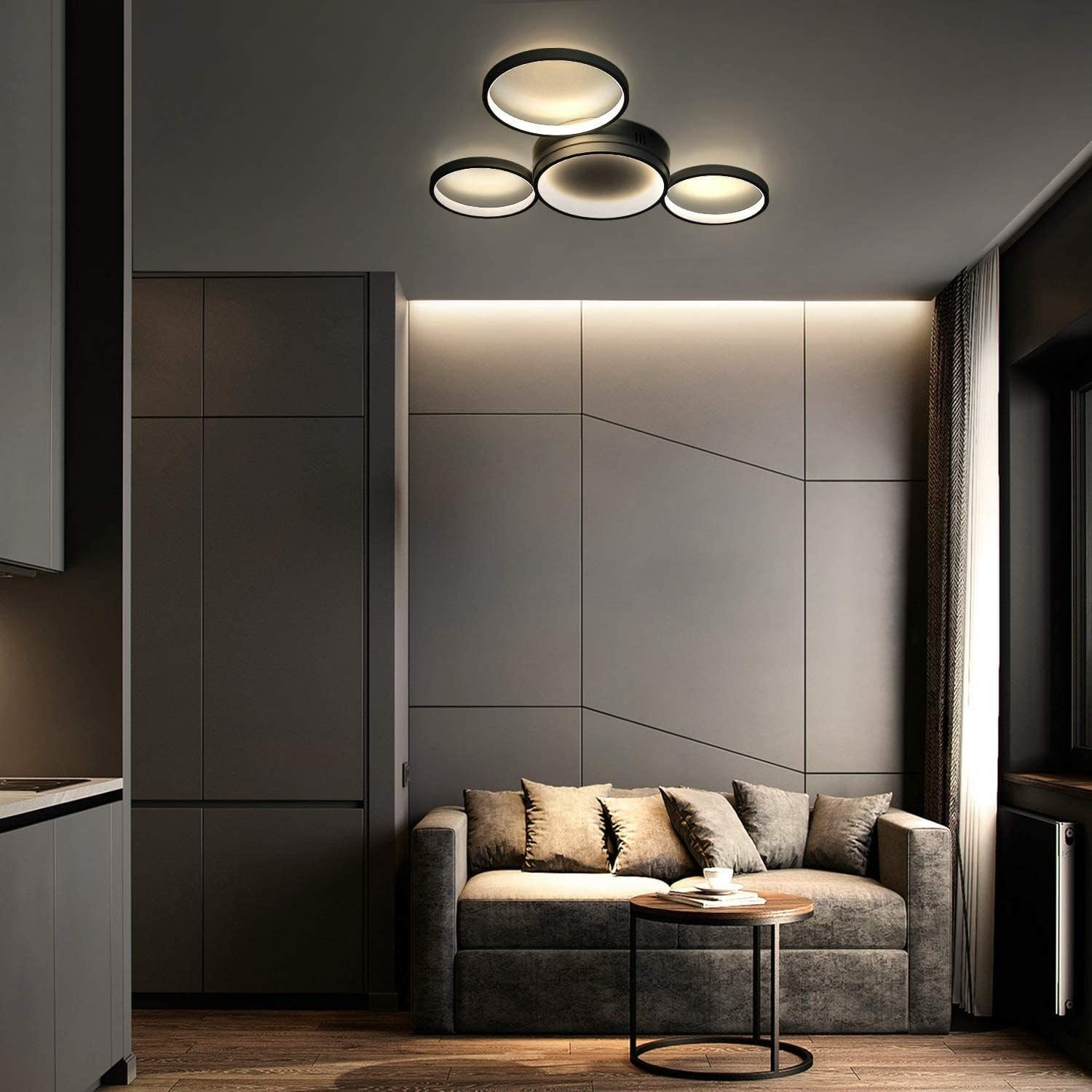 Soggiorno moderno con divano grigio, lampade a soffitto circolari e pareti grigio scuro.