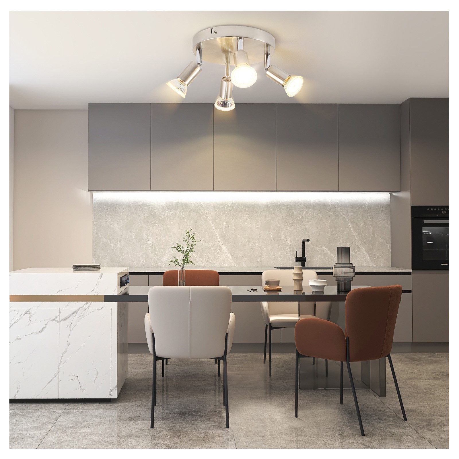 Cucina con faretti sopra un tavolo da pranzo. Sfondo: armadi, alzatina in marmo, sedie e tavolo.