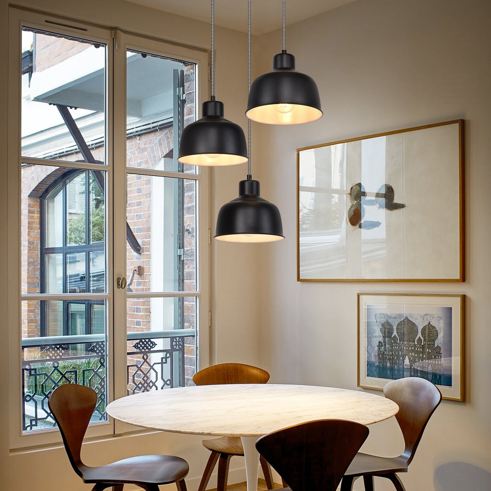 Esszimmer mit drei schwarzen Pendelleuchten, rundem Tisch und Fenster.