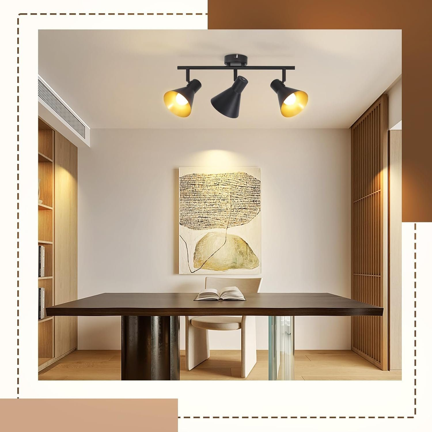 Tre faretti neri su un soffitto bianco, sopra un tavolo di legno scuro. Un dipinto è sulla parete.