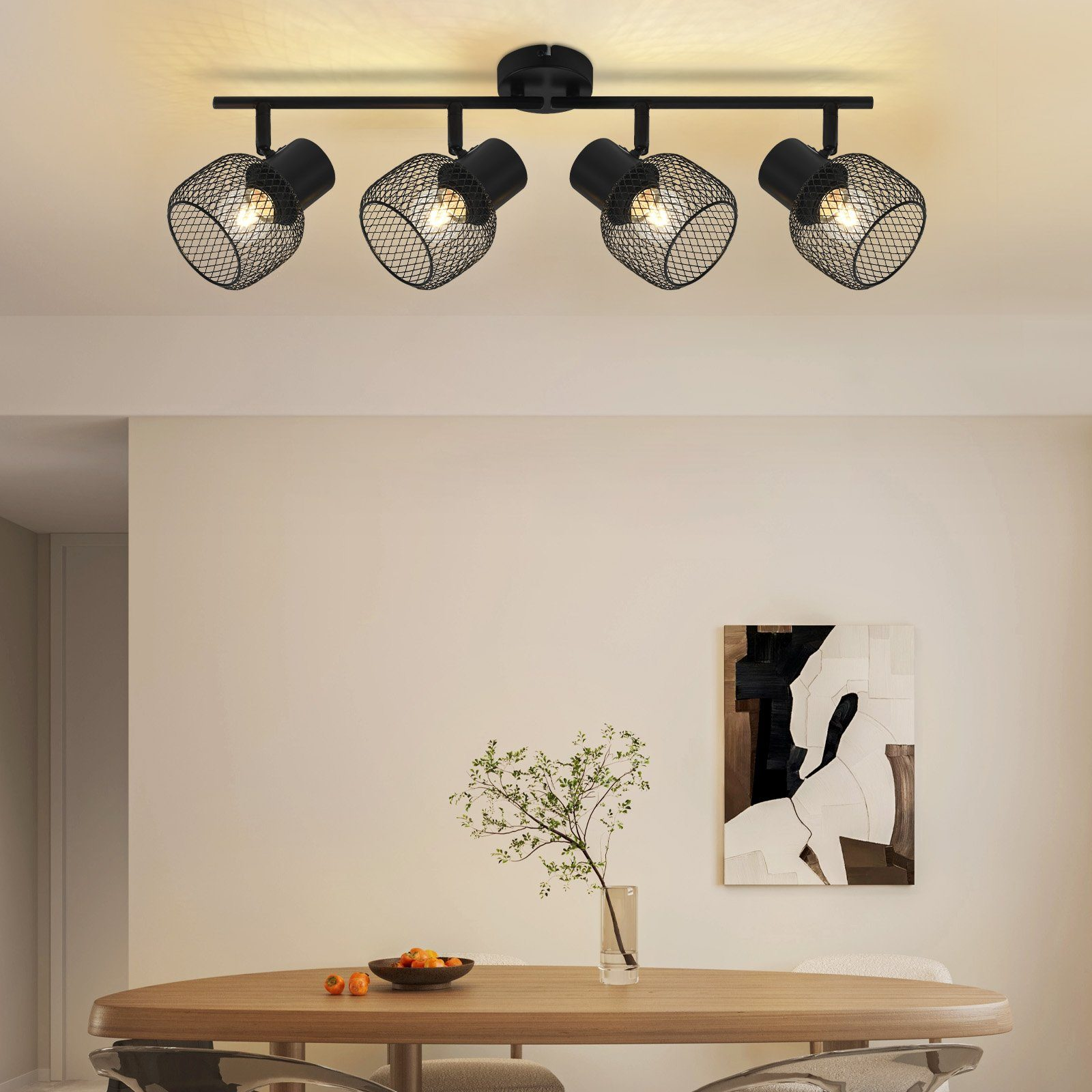 Sala da pranzo con tavolo in legno e quattro faretti neri. Opera d'arte sulla parete.