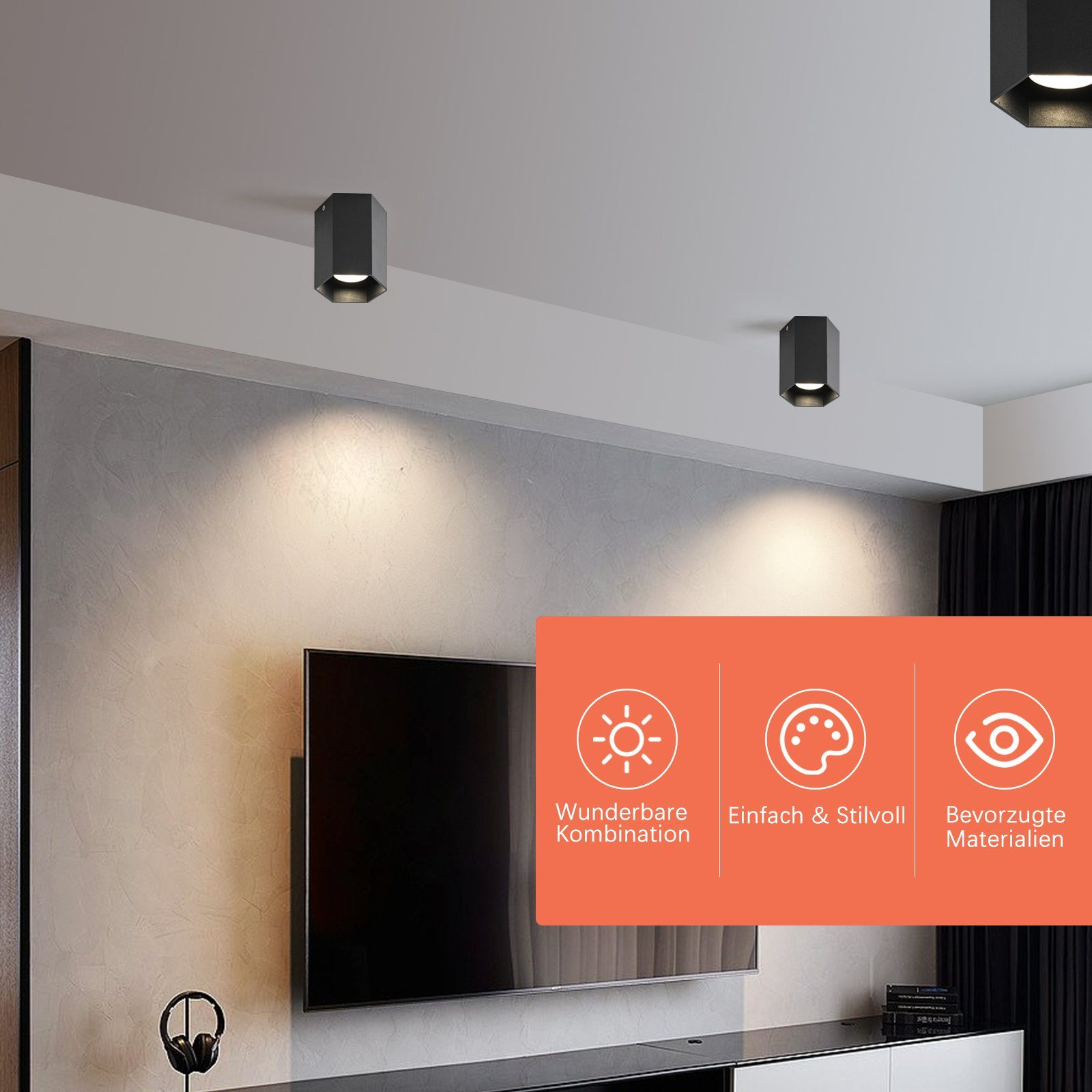 Soffitto con tre luci nere. Le luci sono sopra una TV e altoparlanti. Scatole info arancioni sul muro.