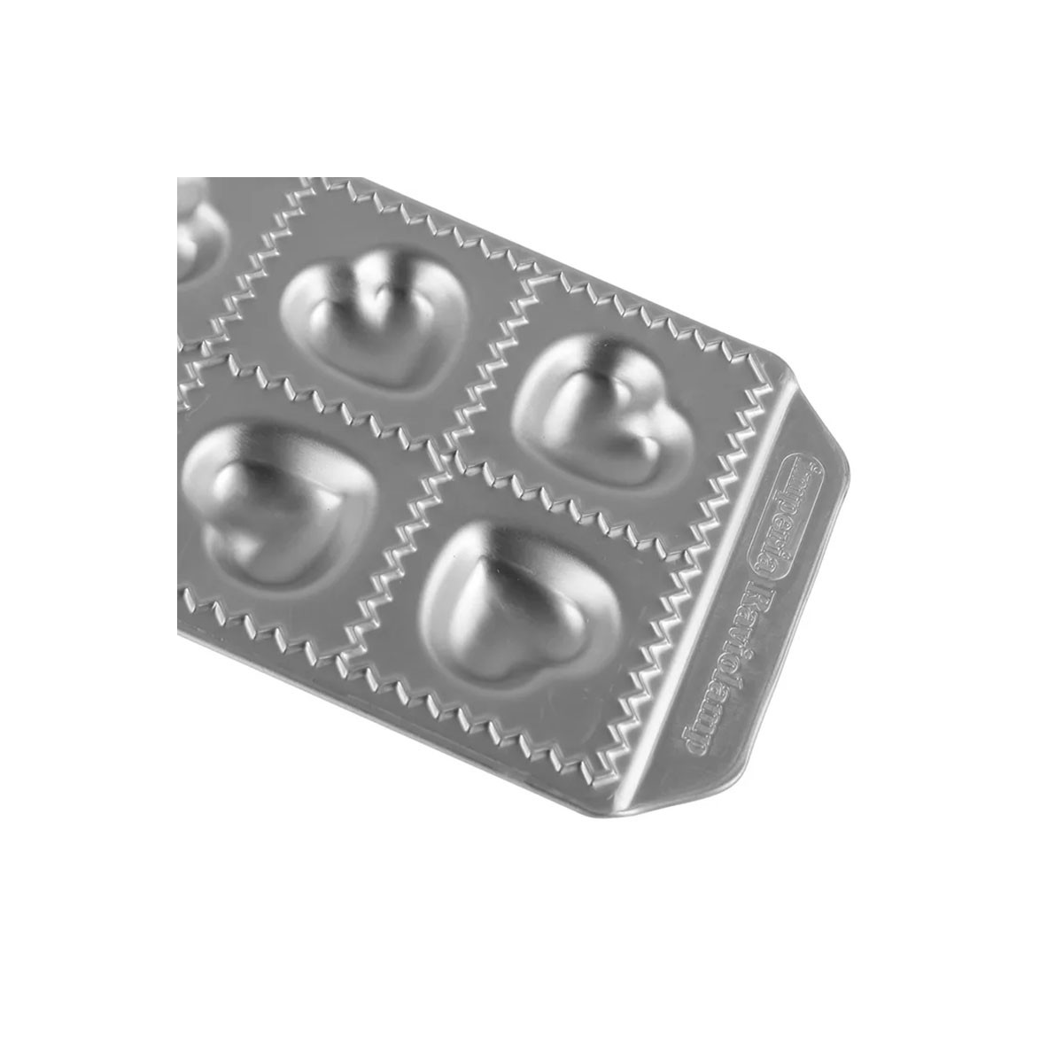 Uno stampo per ravioli argentato con incavi a forma di cuore. Su sfondo bianco.