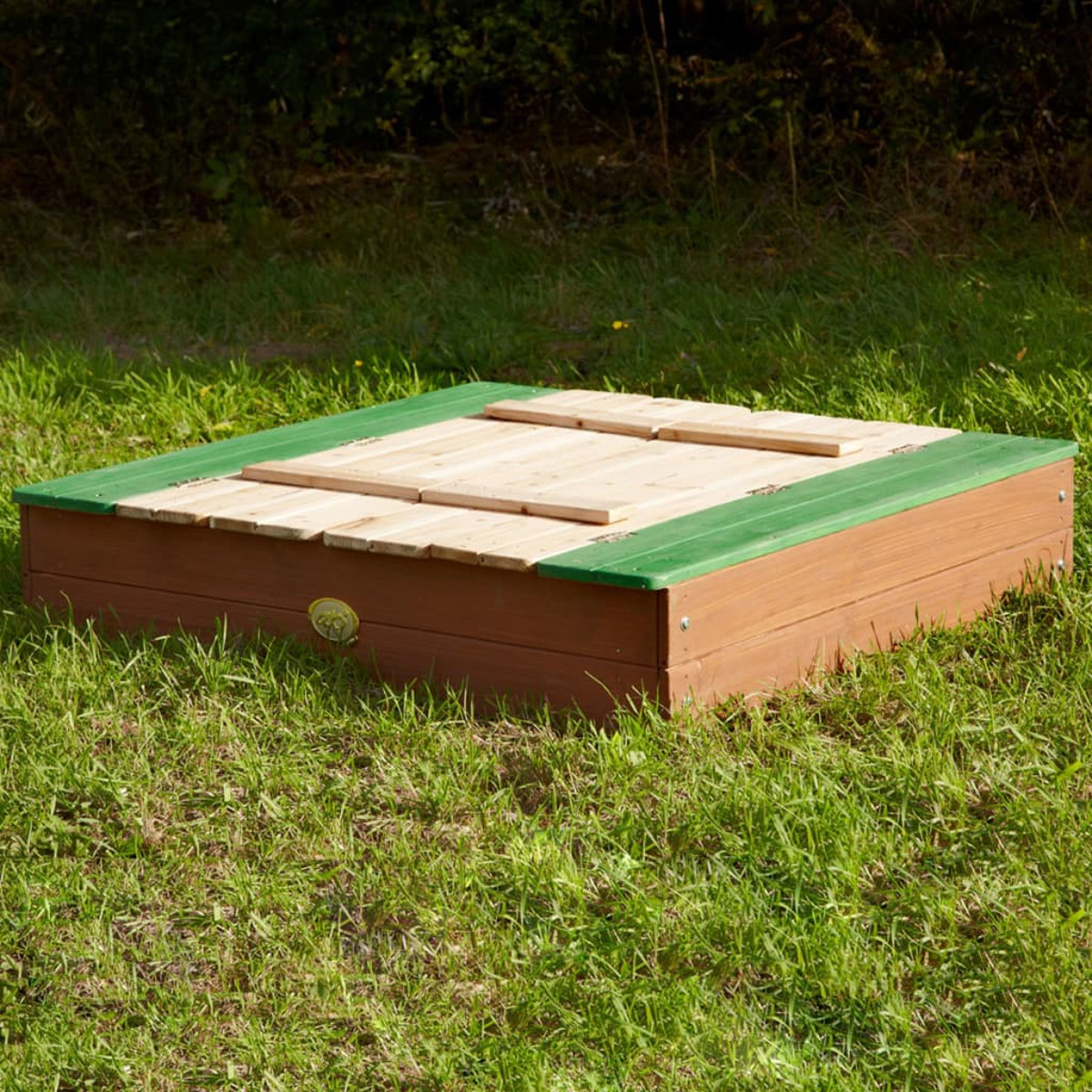 Ein quadratischer Sandkasten aus Holz mit grünem Rand, auf grünem Gras.