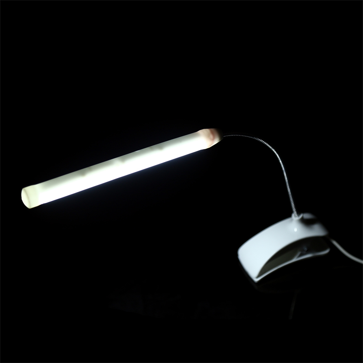 Eine kleine, flexible Lampe mit weißem Sockel und langem, leuchtendem Lichtrohr. Schwarzer Hintergrund.