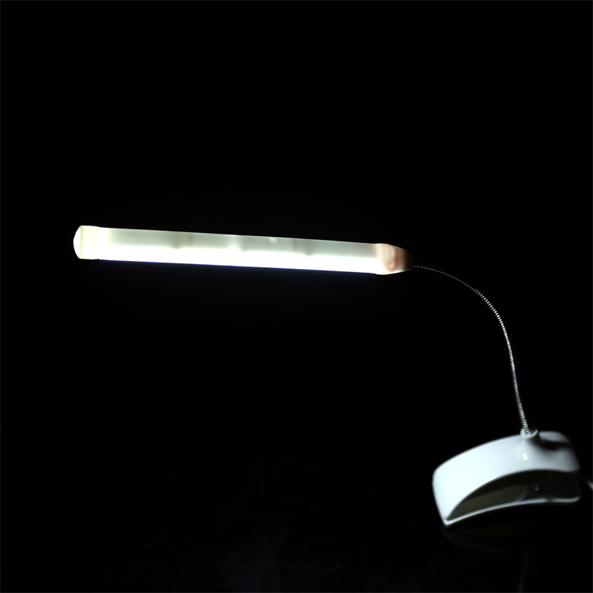 Eine moderne Schreibtischlampe mit weißer Lichtquelle und flexiblem Hals, vor dunklem Hintergrund.
