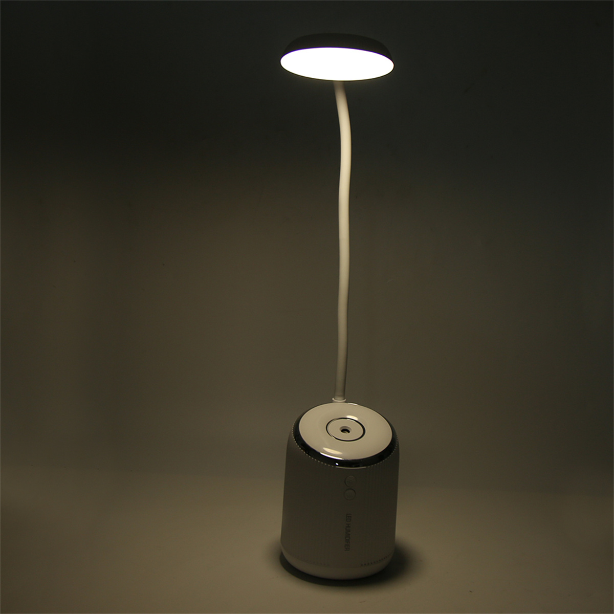 Eine weiße und graue Lampe mit verstellbarem Arm und hellem Licht steht auf einer weißen Oberfläche.