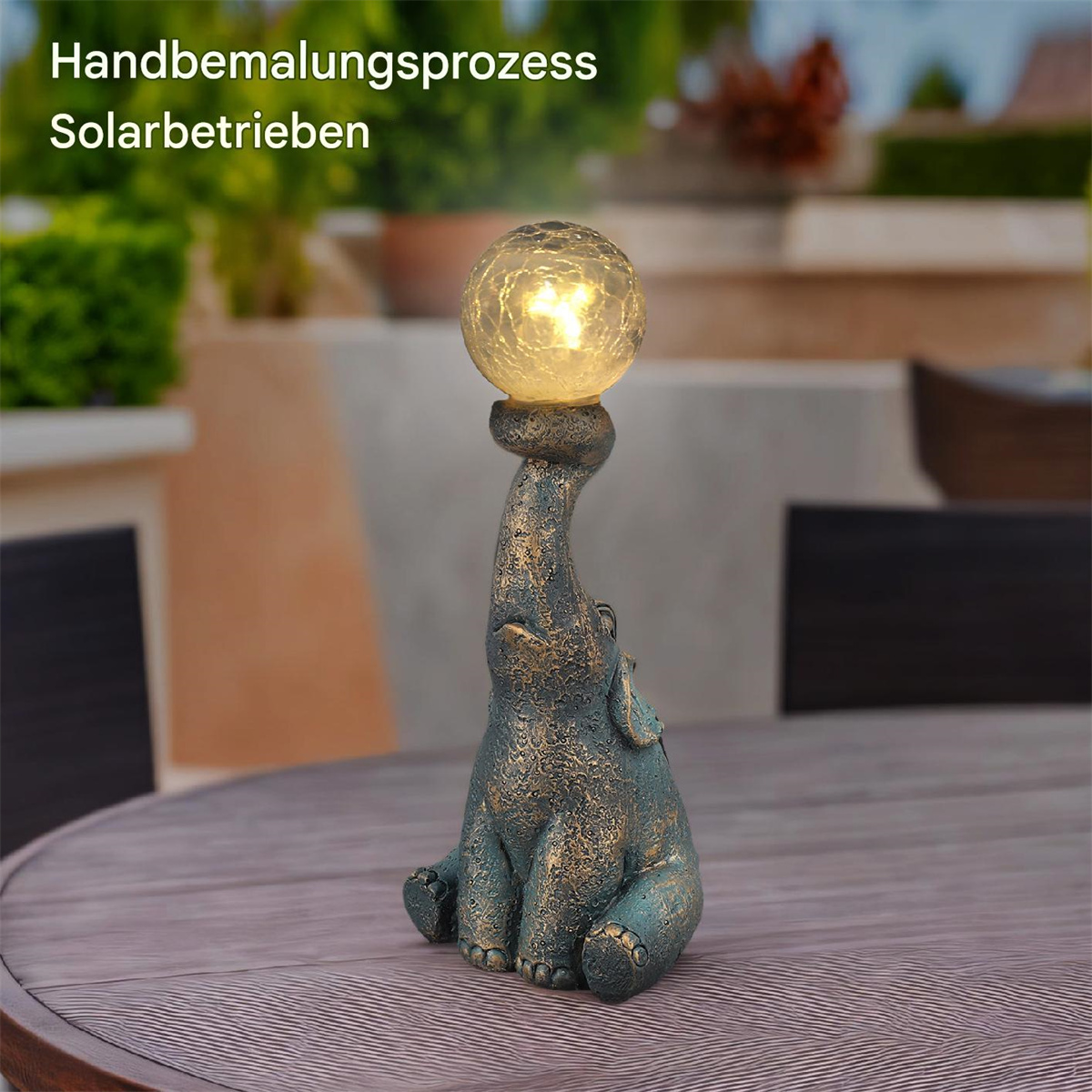 Eine Elefantenfigur, die einen leuchtenden Ball auf einem Holztisch hält.