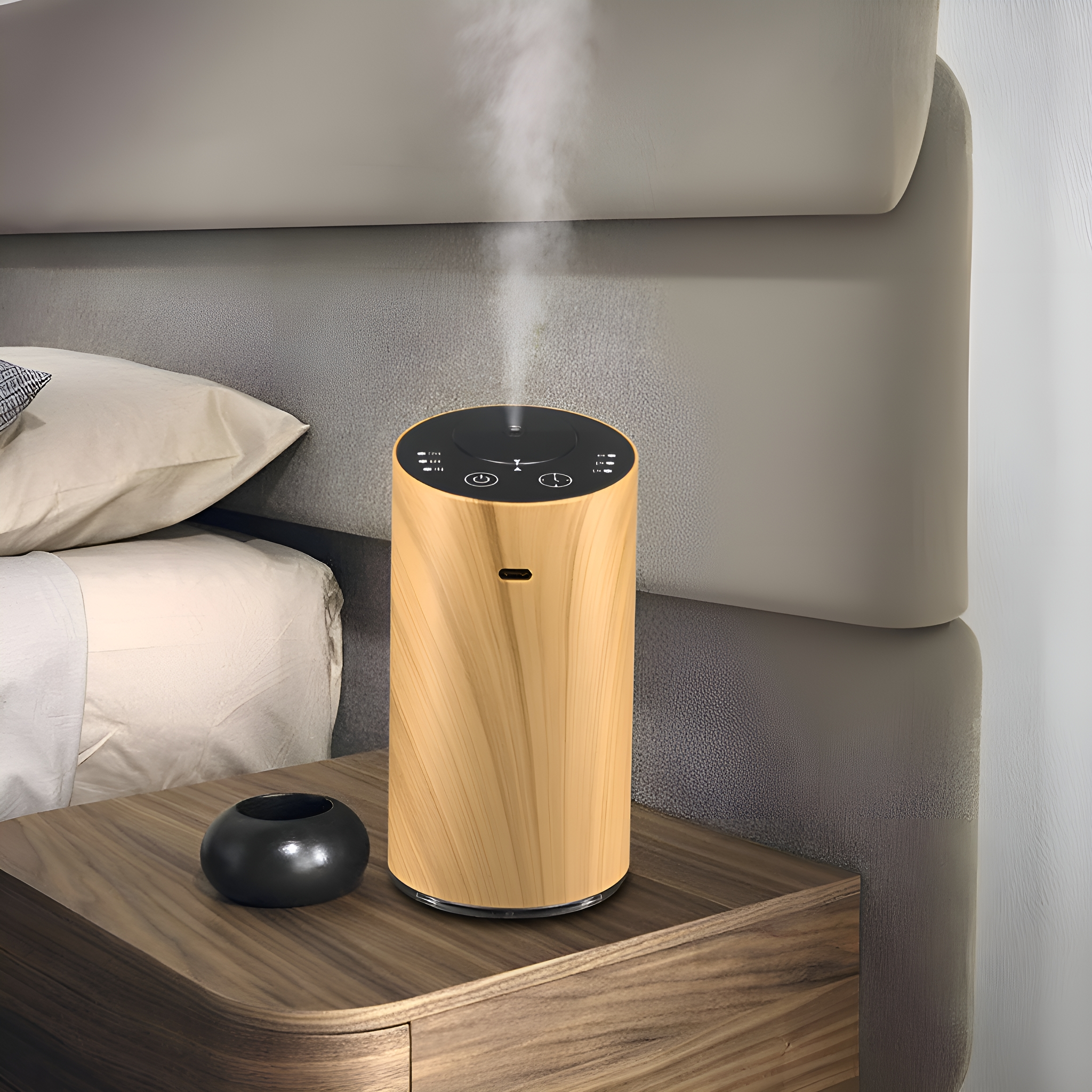 Ein holztexturierter Luftbefeuchter auf einem Nachttisch, mit aufsteigendem Dampf. Eine schwarze Vase steht daneben.