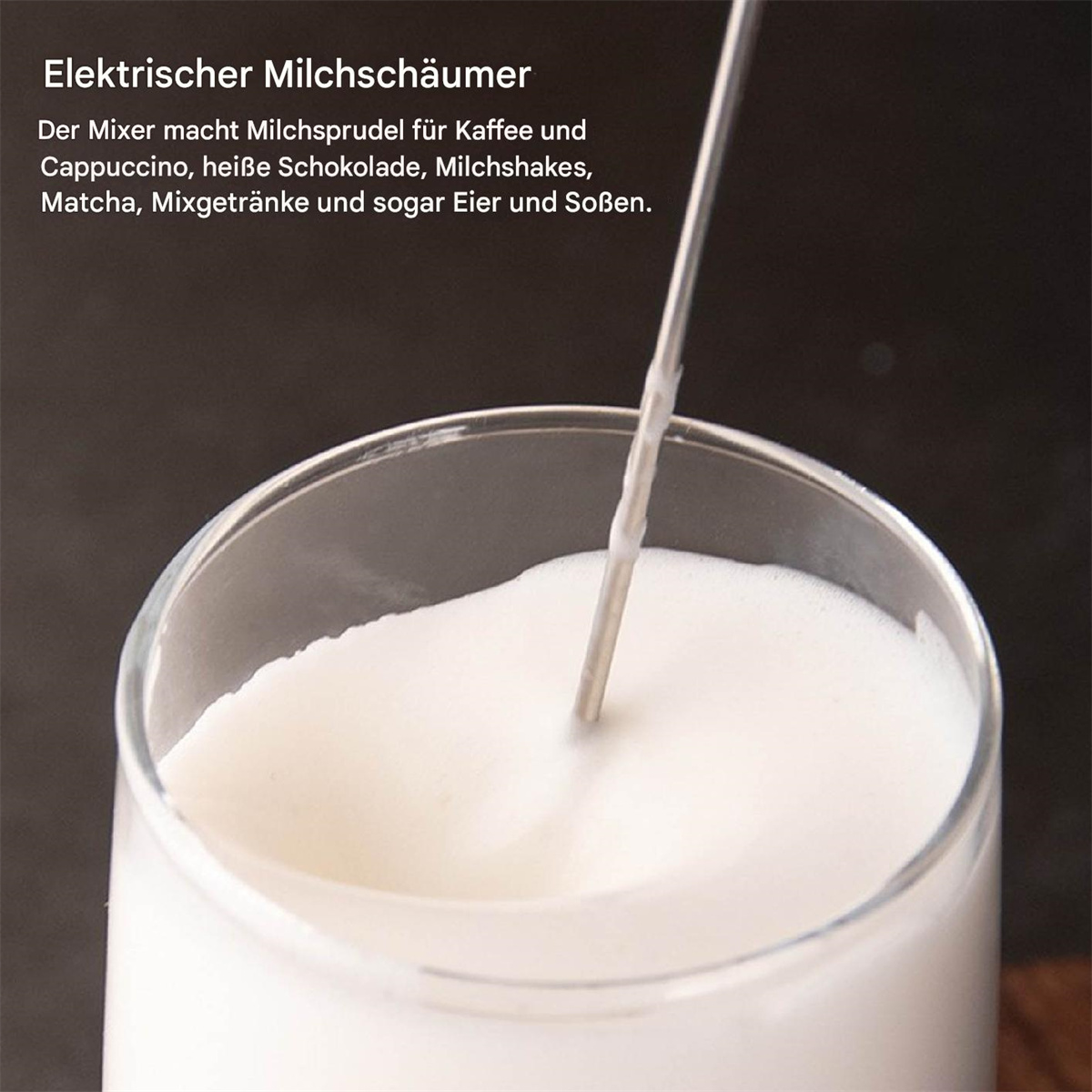 Elektrischer Milchaufschäumer in einem Glas. Schaum oben, silberner Stab innen. Dunkler Hintergrund.