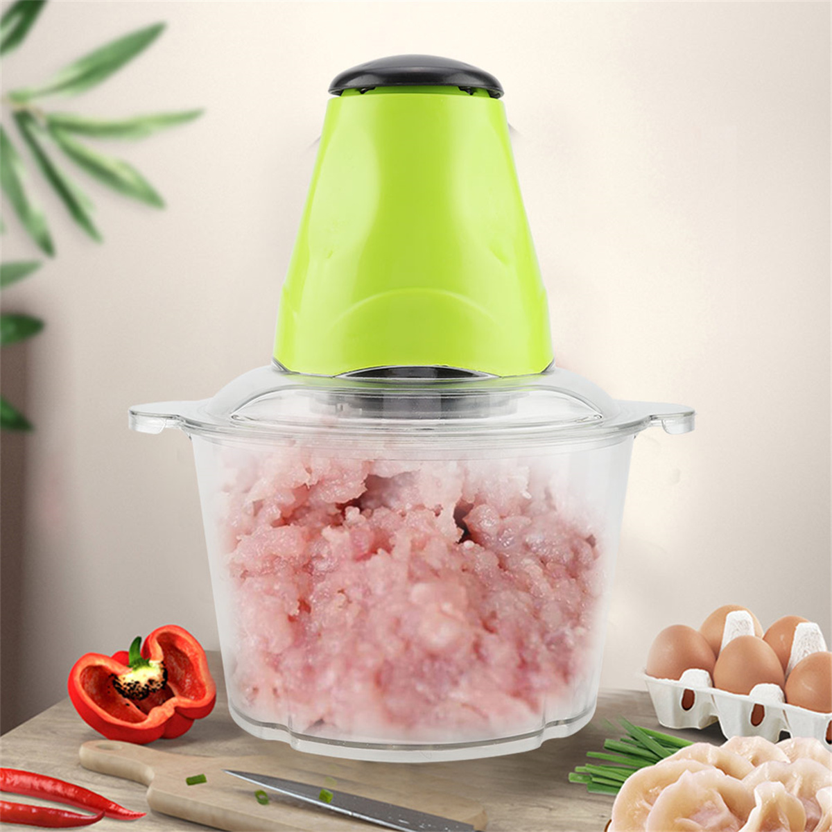 Ein grüner Zerkleinerer mit Hackfleisch. Gemüse und Eier umgeben den Zerkleinerer.