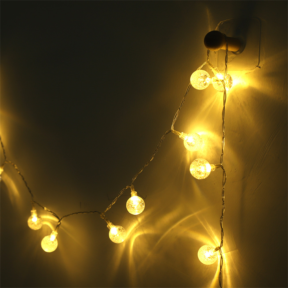 Eine Lichterkette mit kleinen, runden, beleuchteten Lichtern an einer Wand, die ein warmes, einladendes Leuchten erzeugen.