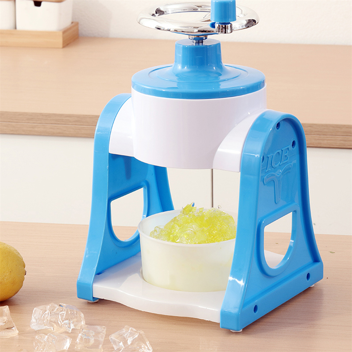 Blau-weiße Eisschabemaschine mit Eis und Zitrone, auf weißer Oberfläche.