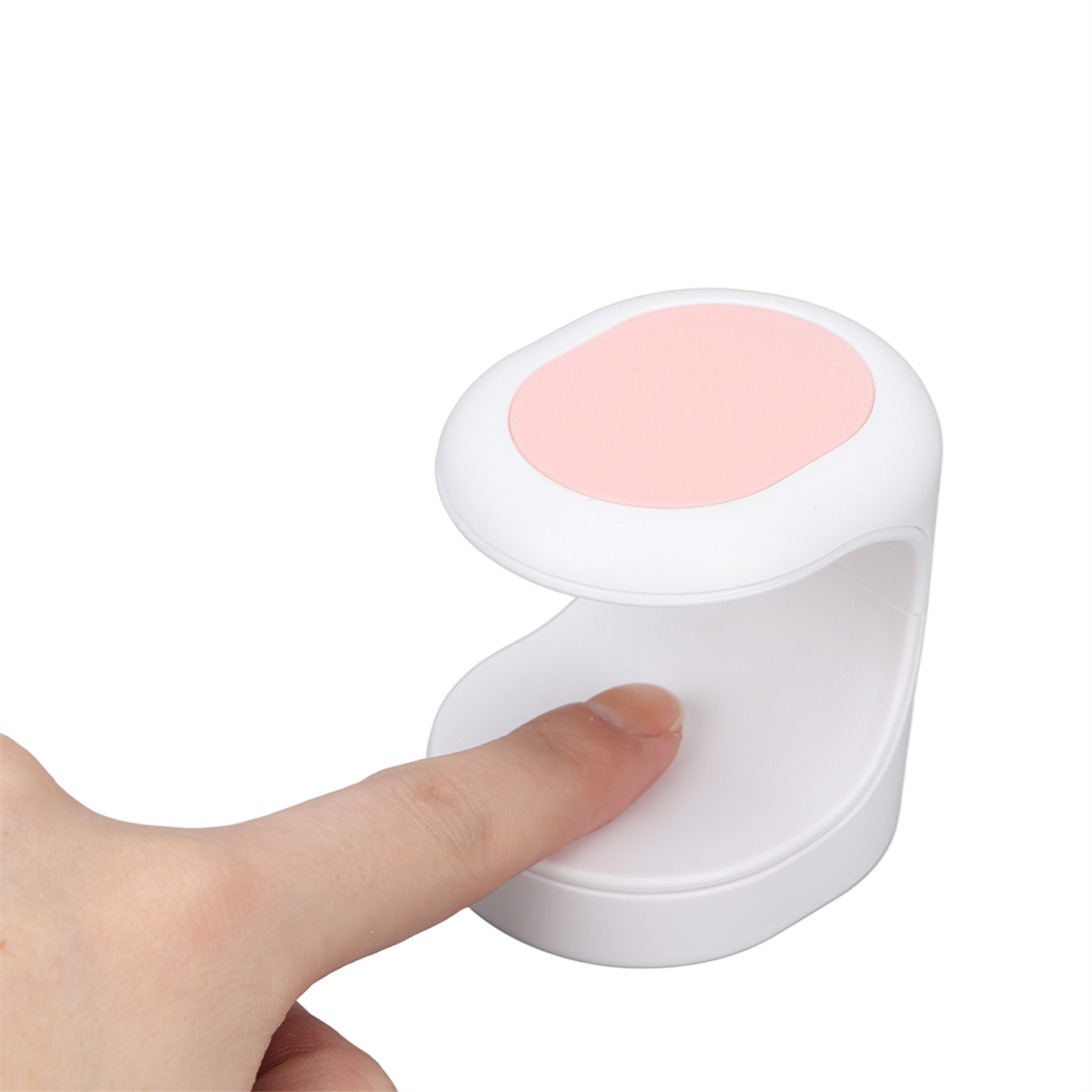 Ein weißer Nageltrockner mit rosa Oberteil wird von einer Hand mit einem Finger darin benutzt.