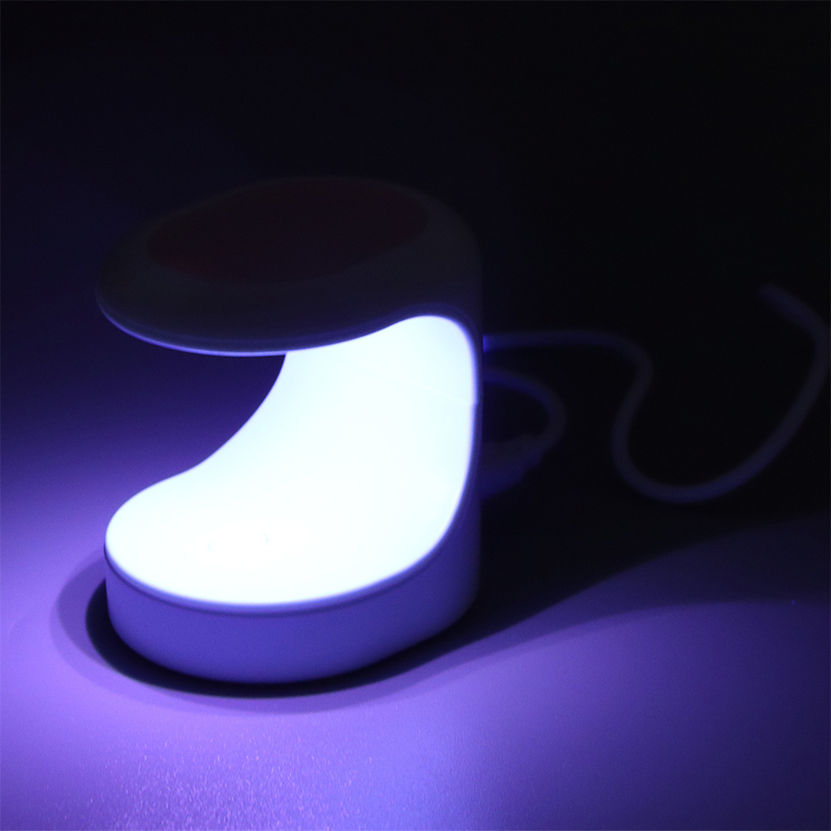 Eine weißes Nagellampe leuchtet hell und emittiert violettes Licht auf eine violette Oberfläche in einer dunklen Umgebung.