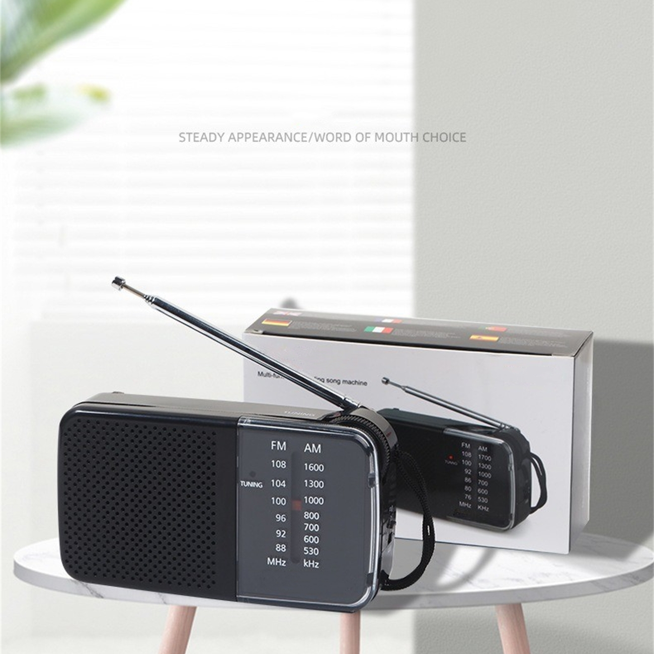 Schwarzes Radio mit Drehkopf, Antenne und einer Box mit einem ähnlichen Radiobild auf einem Tisch.