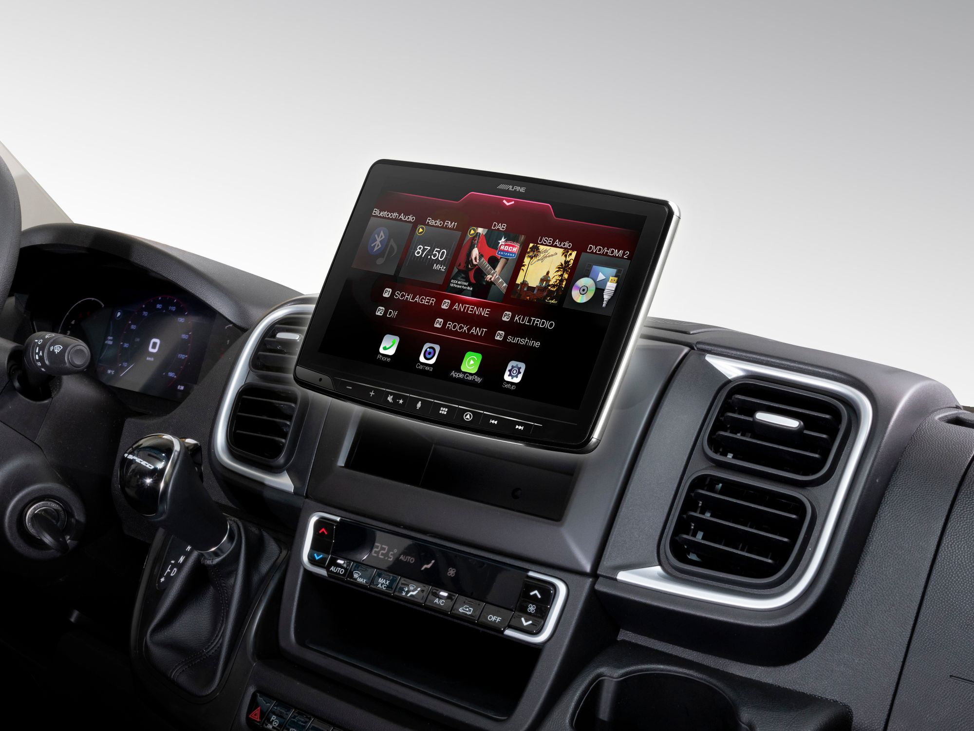 Das Armaturenbrett eines Autos mit einem Alpine Autoradio-Bildschirm, der Radiosenderinformationen anzeigt.