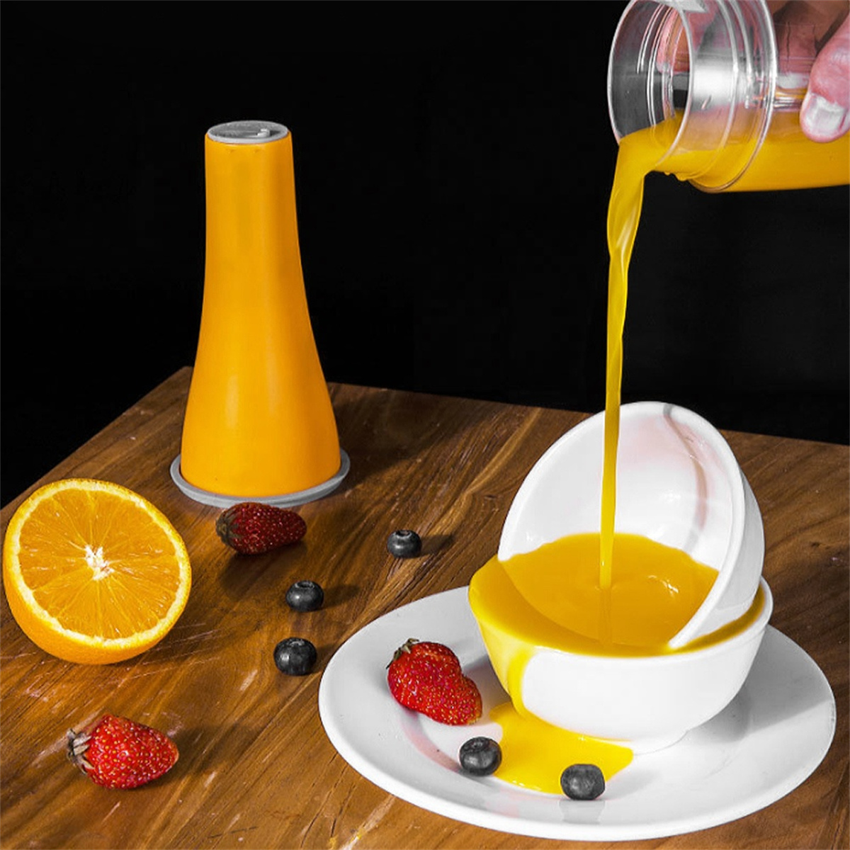 Orangensaft wird in eine weiße Schüssel mit Erdbeeren und Blaubeeren gegossen.