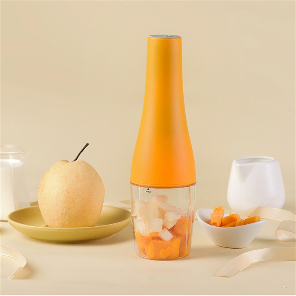 Ein Foodprocessor mit gewürfeltem Obst und eine Birne auf einem Teller.