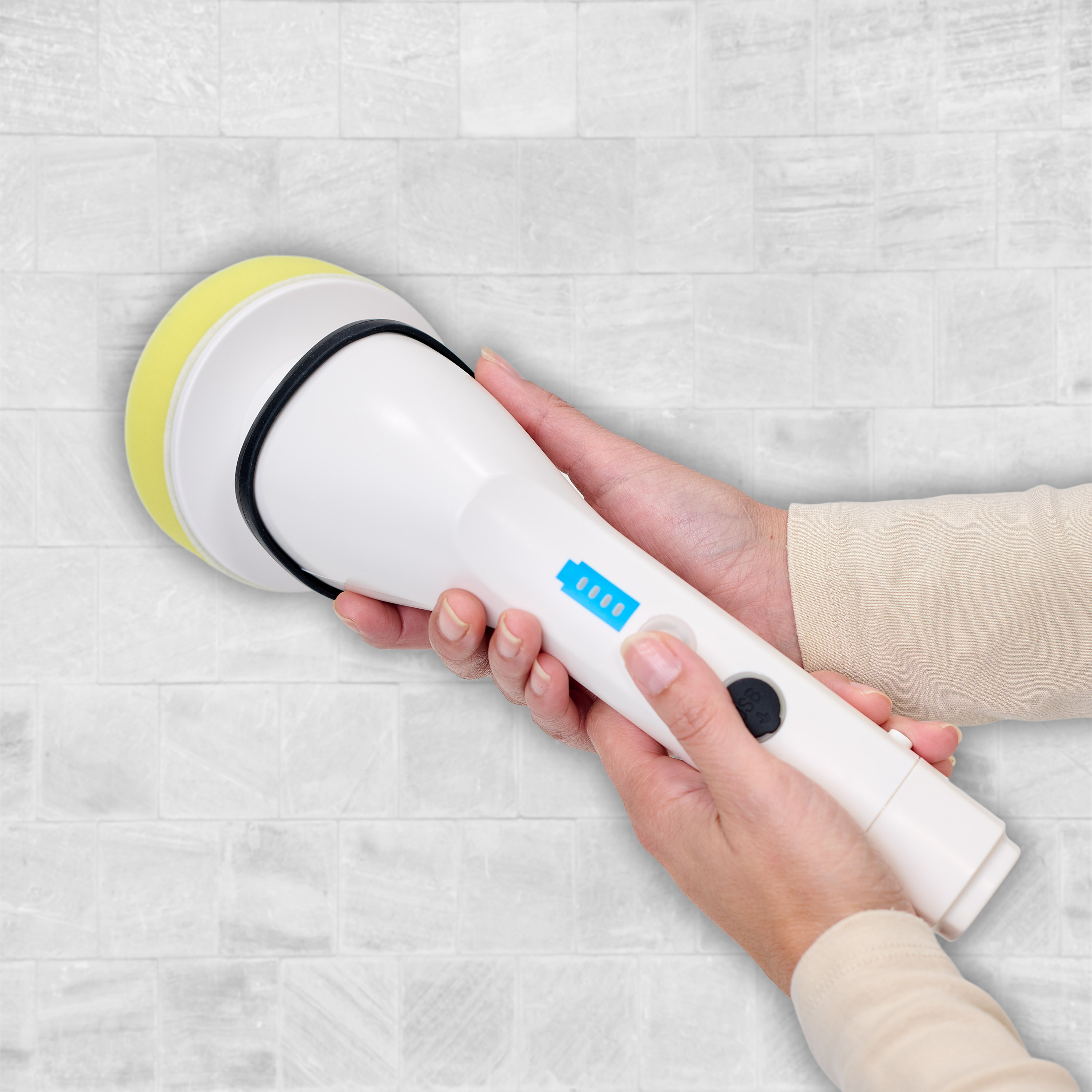 Hands holding a white cleaning brush. The brush has a yellow cleaning head and a blue power indicator.
