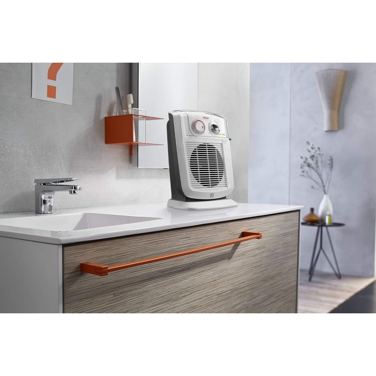 Un termoventilatore bianco e grigio su un piano di lavoro. Si vedono uno specchio e un portasciugamani.