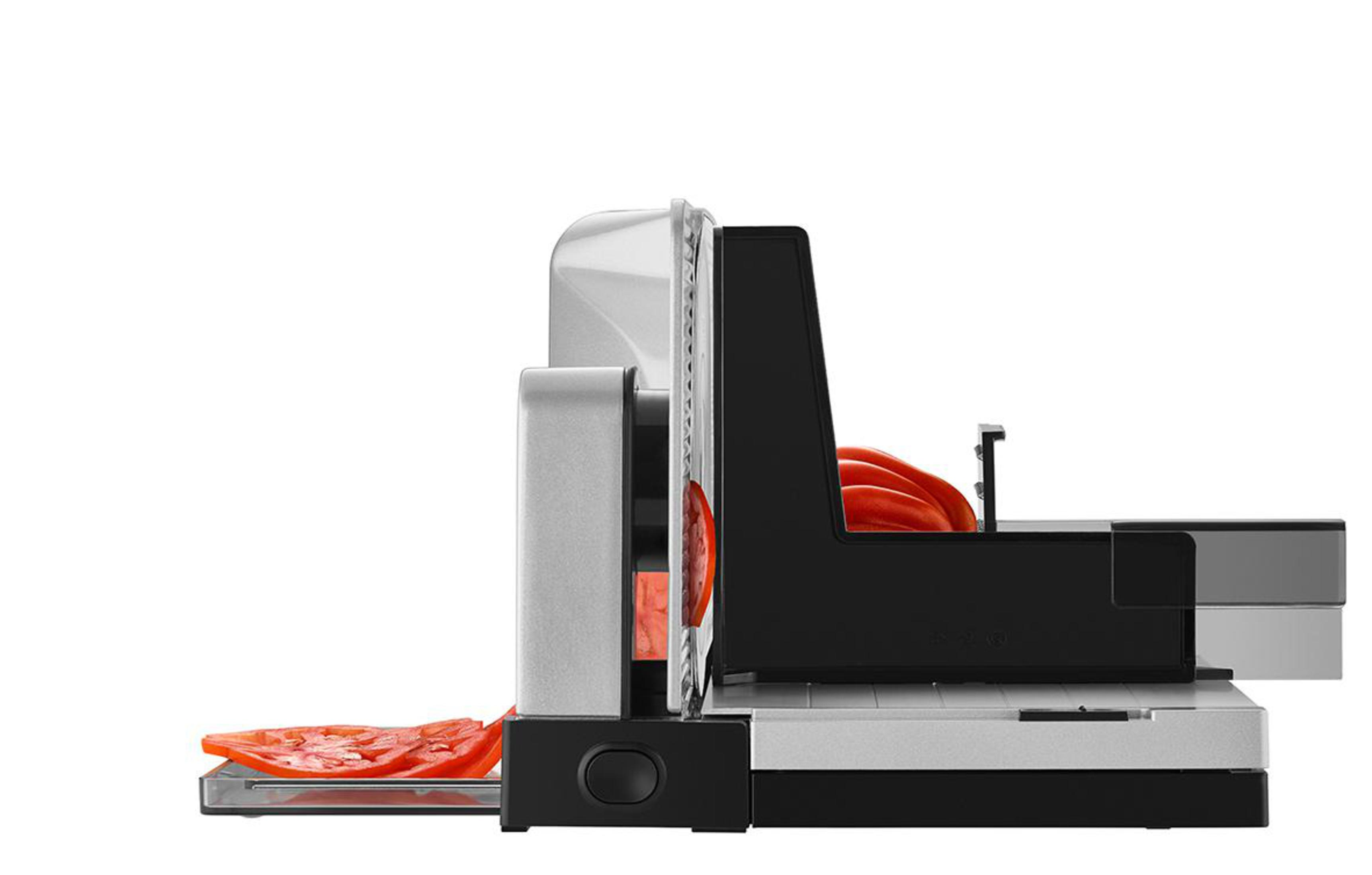 Widok z boku krajalnicy do żywności z krojonym pomidorem, z czerwoną plasterkiem pomidora.