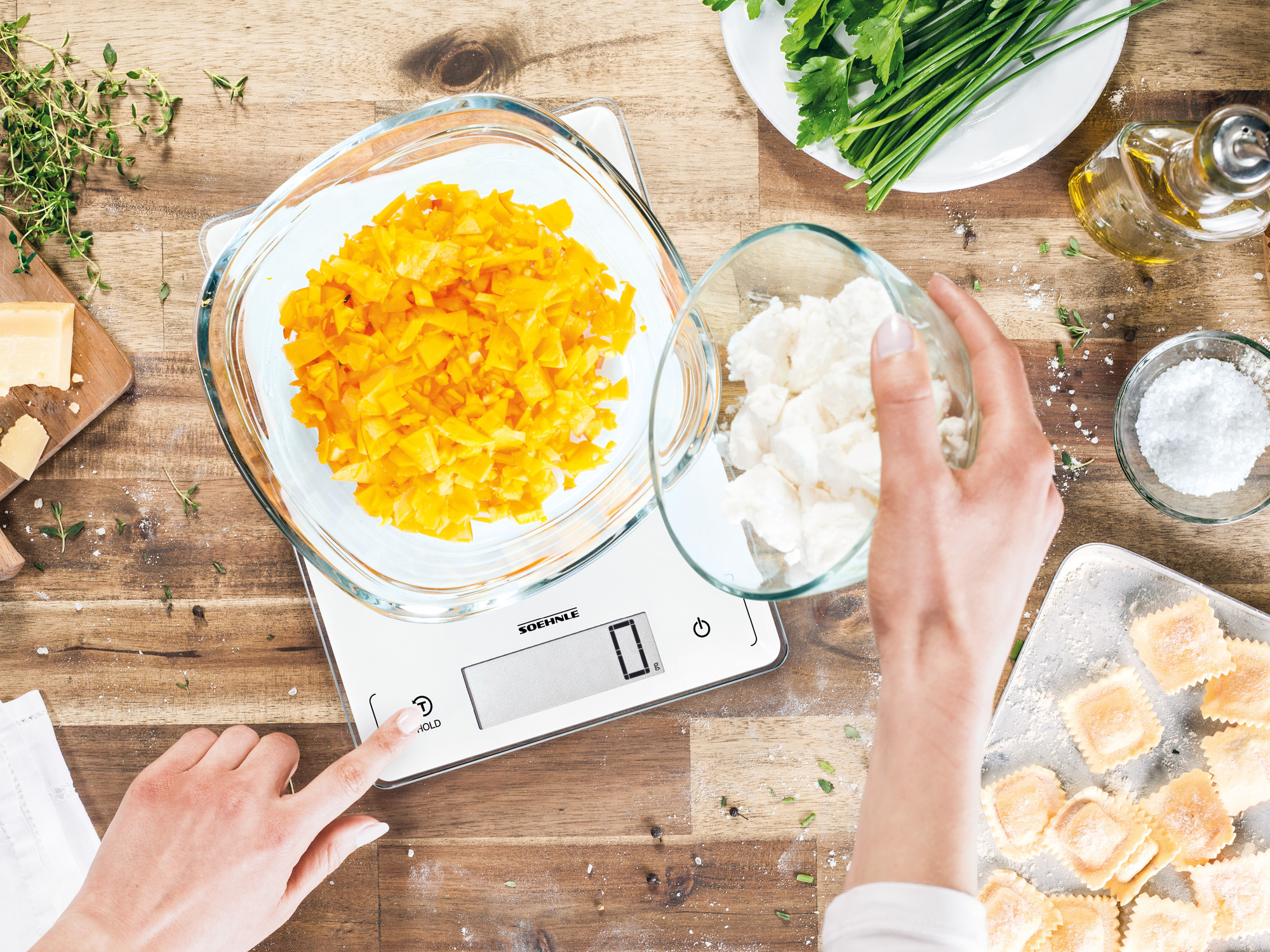 Scena kuchenna: Waga z miską pomarańczowej papryki, inne składniki i ręce osoby.