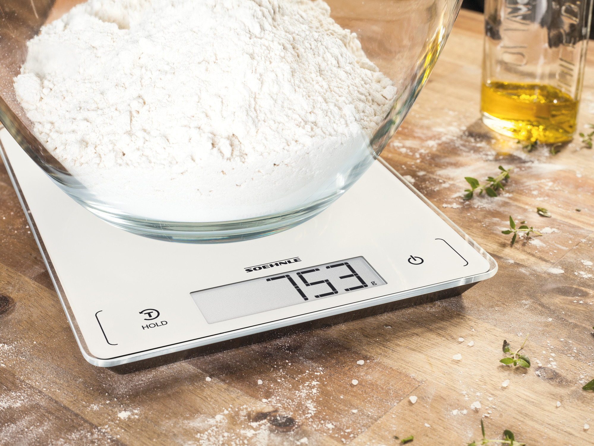 Biała cyfrowa waga kuchenna z miską mąki i oliwy z oliwek, ważąca 753 gramy.