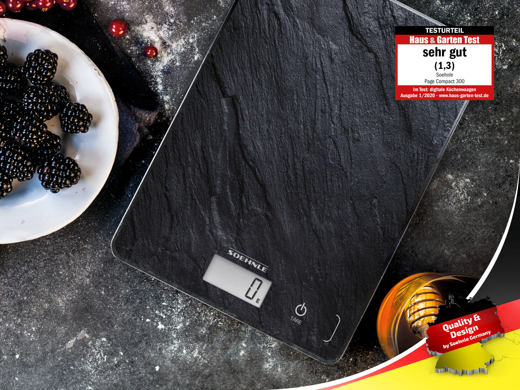 Czarna, łupkowa waga kuchenna z wyświetlaczem '0.0', obok talerza jeżyn.