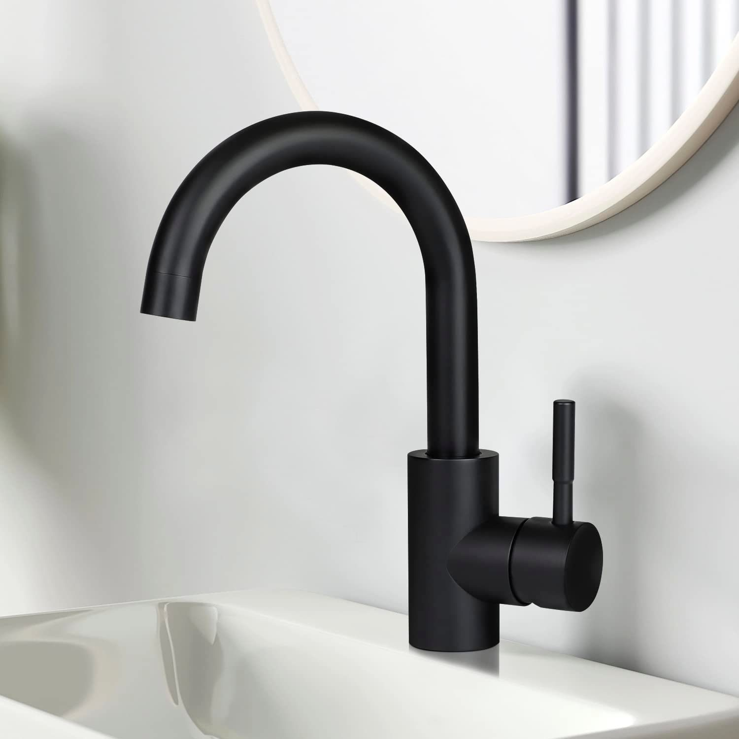 Schwarzer Wasserhahn über einem weißen Waschbecken. Runder Spiegel im Hintergrund. Weiße Wand.