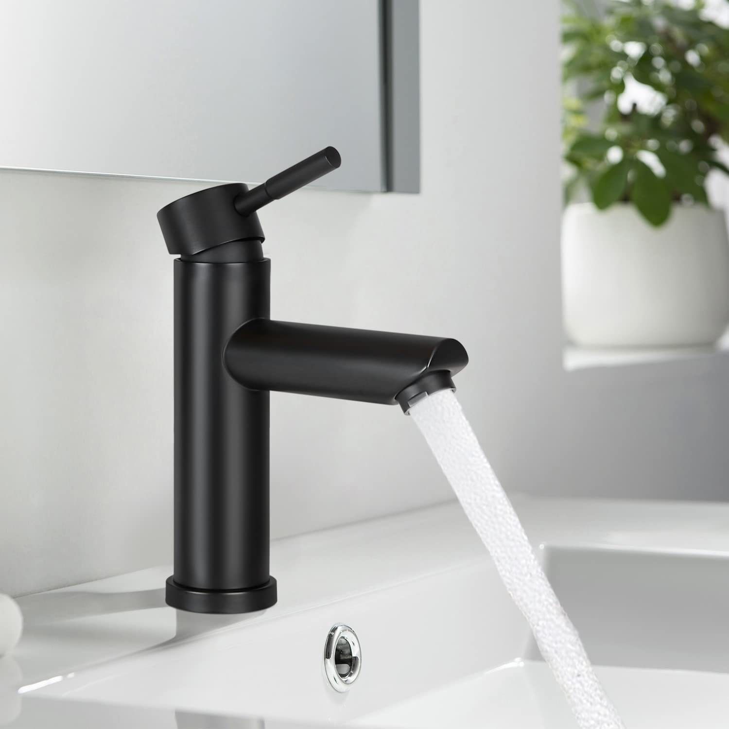 Schwarzer Wasserhahn mit Wasserstrahl, der in ein weißes Waschbecken fließt, mit Spiegel im Hintergrund.