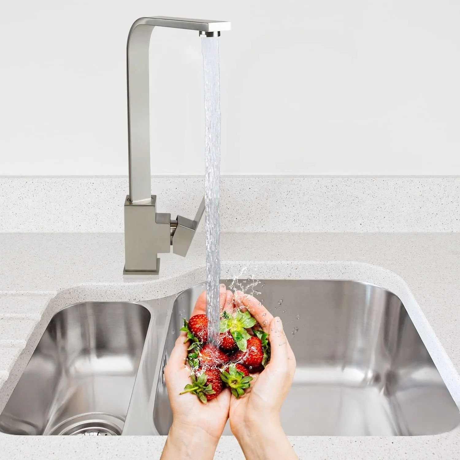 Ein Küchenbecken mit Wasserhahn, der Wasser über Hände gießt, die Erdbeeren halten.