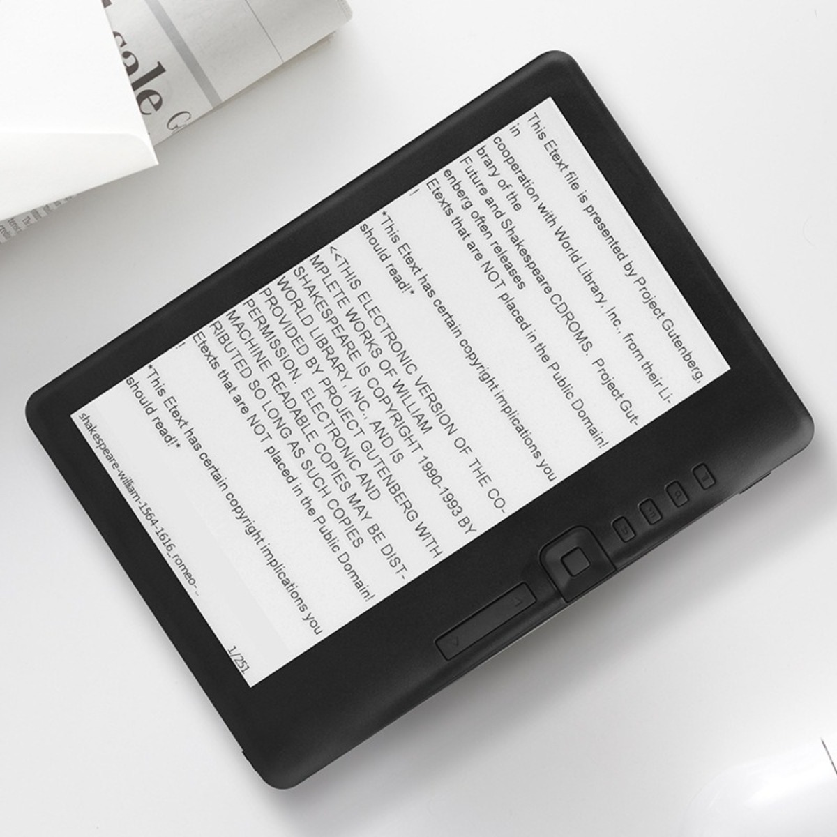 Ein E-Reader mit Text auf dem Bildschirm. Das Gerät ist schwarz und liegt auf einer weißen Oberfläche.