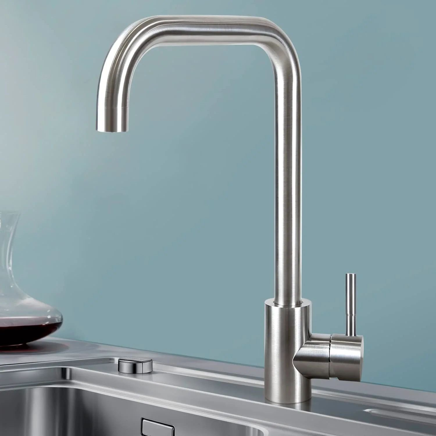 Primo piano di un rubinetto da cucina cromato su sfondo azzurro.