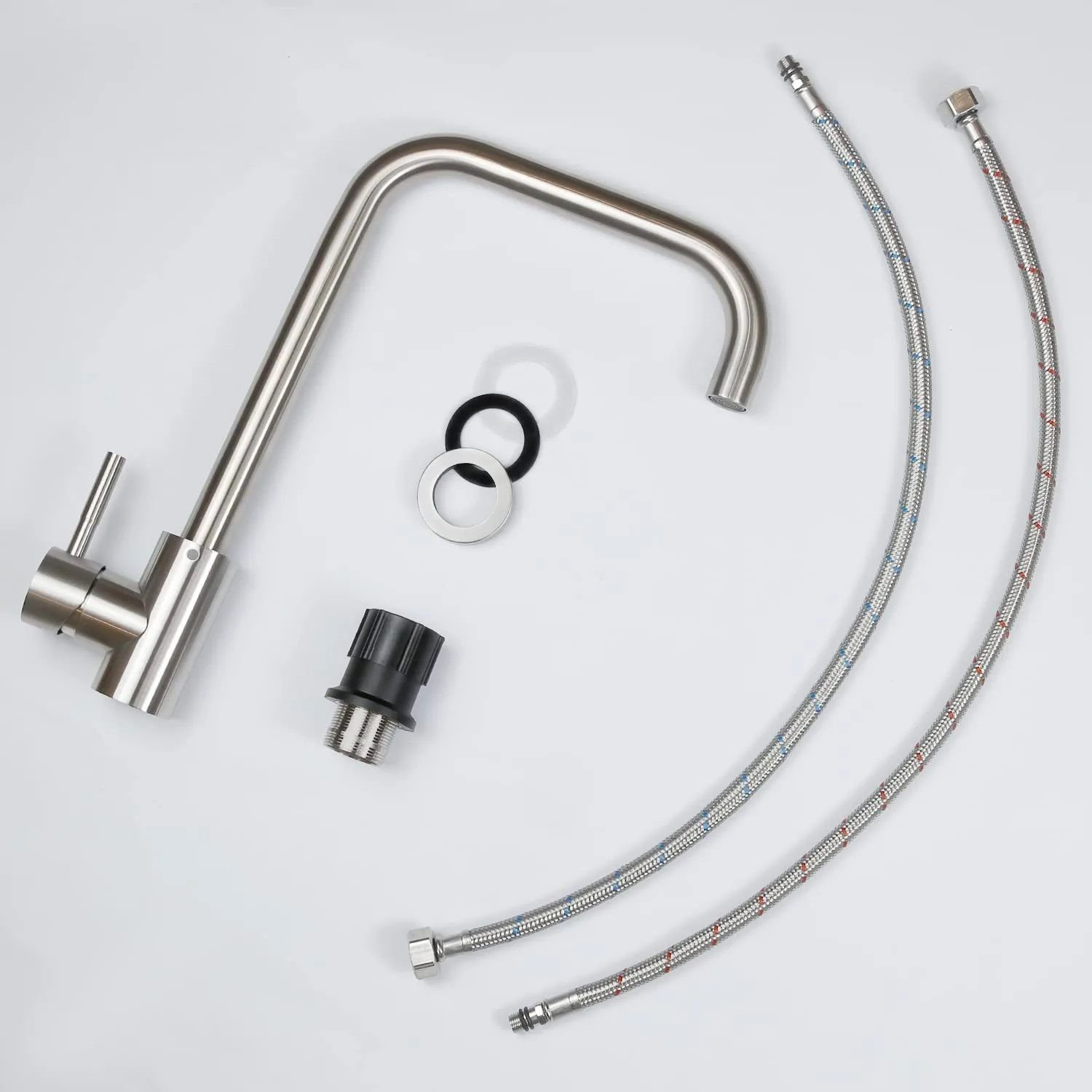 Rubinetto da cucina in acciaio inox con due tubi flessibili e altri componenti su superficie bianca.