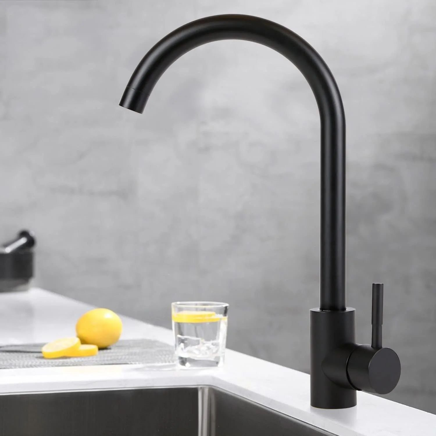 Schwarze Küchenarmatur mit gebogenem Auslauf. Glas Wasser, Zitronenscheiben. Grauer Hintergrund.