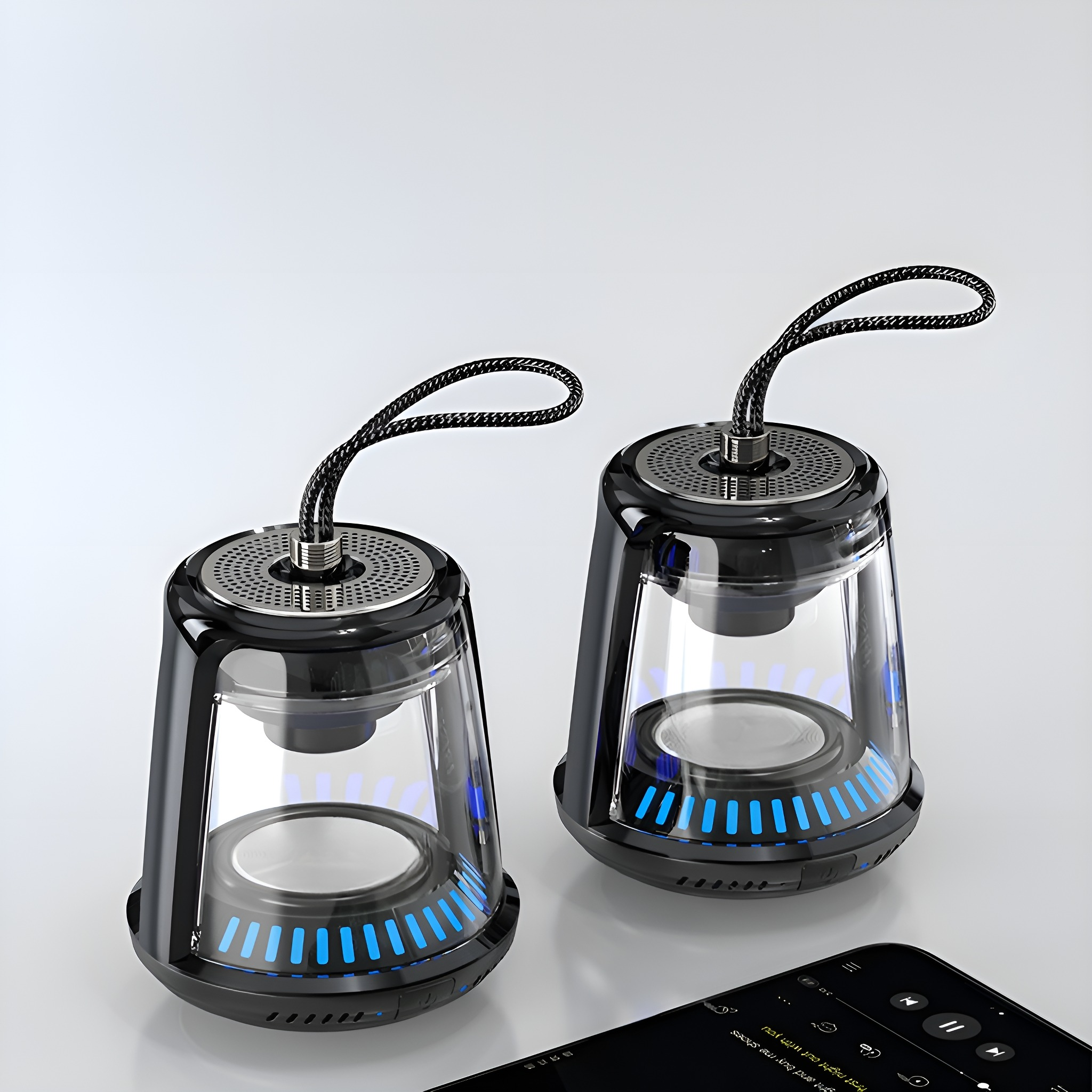 Zwei transparente Lautsprecher mit blauen Lichtern neben einem Musik abspielenden Telefon.