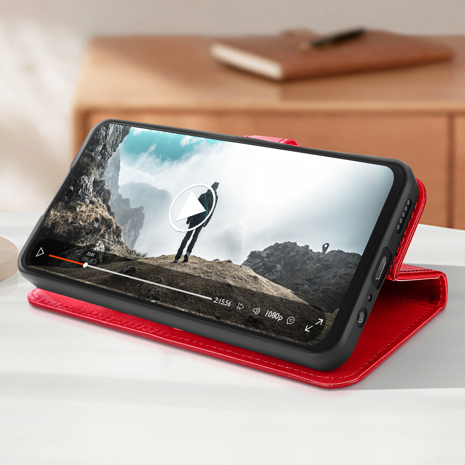 Smartphone in una custodia rossa che mostra un video di una persona in montagna.