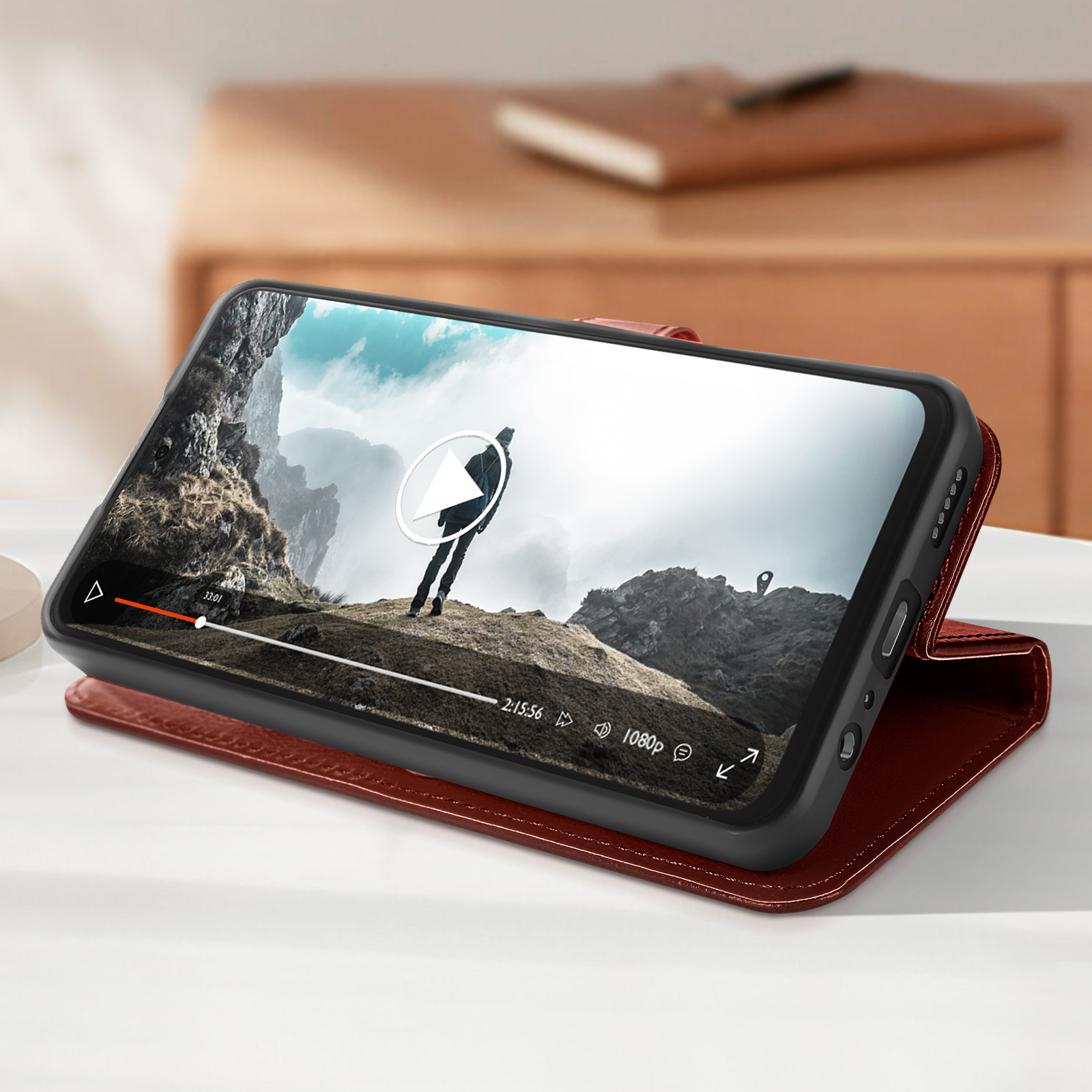 Smartphone in custodia rossa, riproduce un video. Tavolo marrone e sfondo in legno.