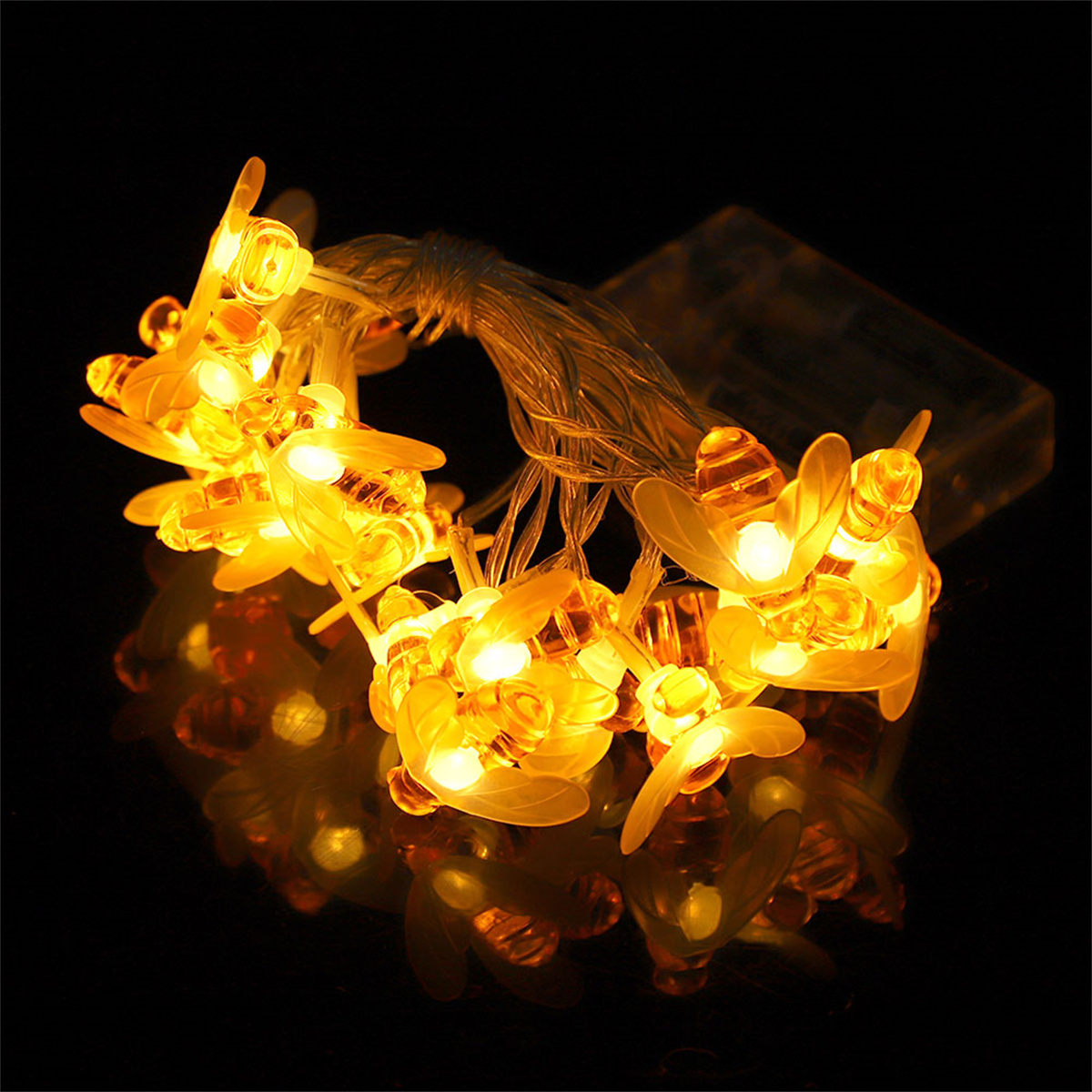 Bienenförmige Lichterkette mit gelben Lichtern auf schwarzer Oberfläche. Klarer Draht und Batteriepack sichtbar.