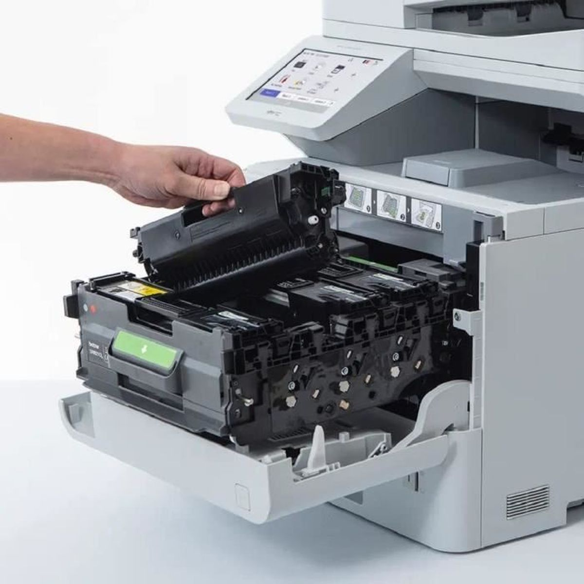 Une personne insérant une cartouche de toner noire dans une imprimante blanche et grise.