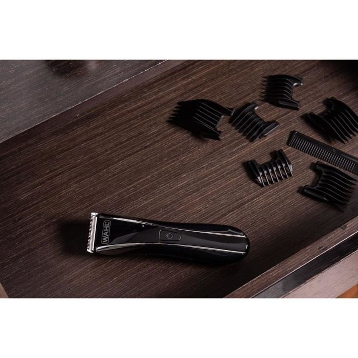 Tagliacapelli nero con più accessori, su una superficie di legno all'interno di un cassetto.