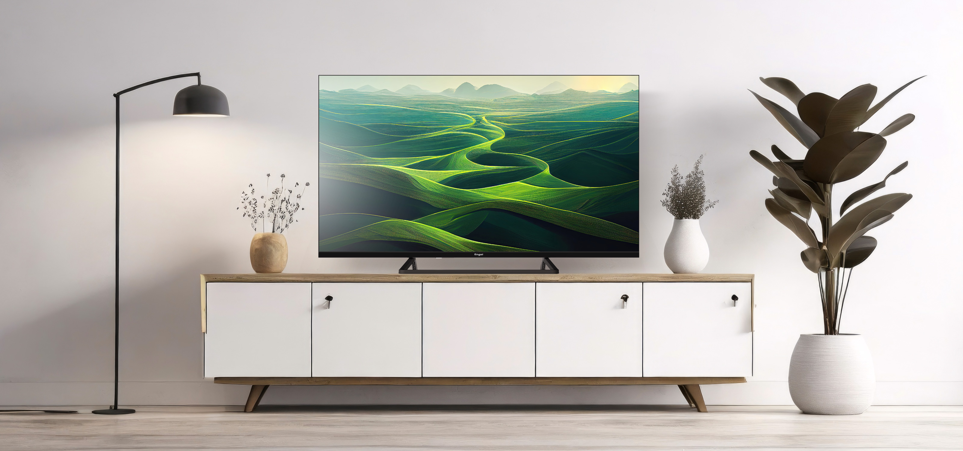 Un televisor que muestra un paisaje de colinas verdes, colocado sobre un mueble blanco.