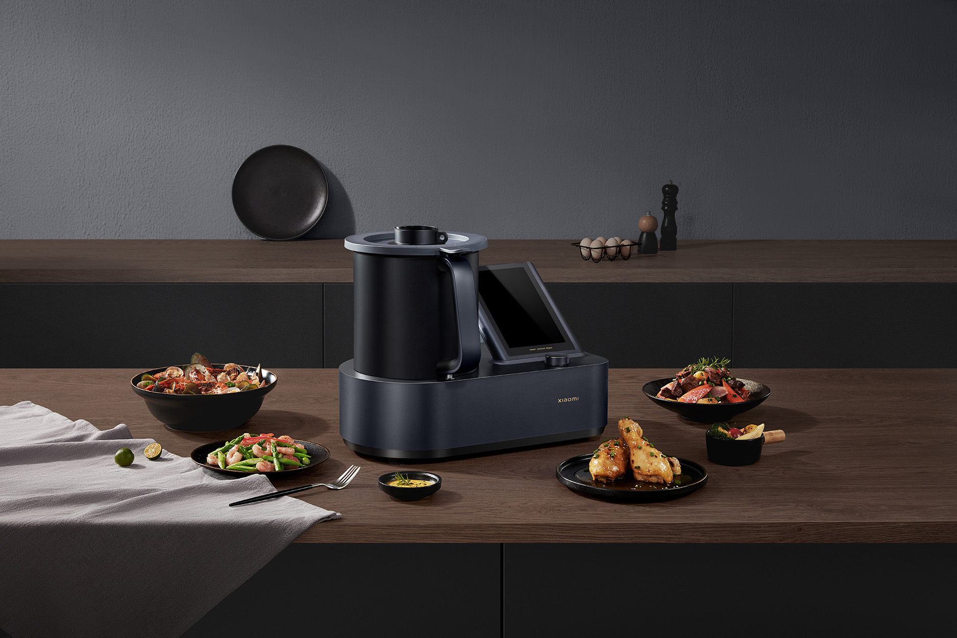 Moderne Küchenszene mit Küchenmaschine, umgeben von Gerichten auf Holzoberfläche.